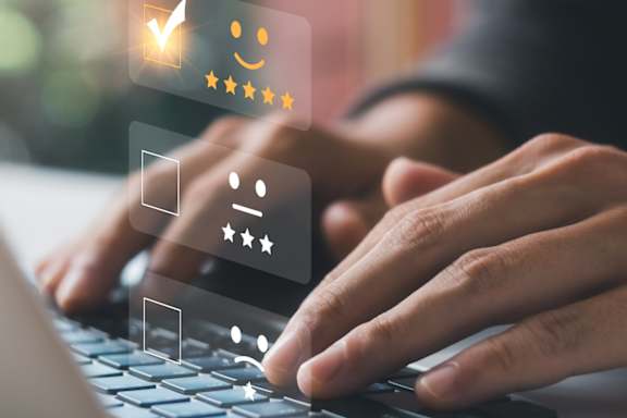 A person typing on a laptop with a graphic of a checkmark and stars appearing on the screen.