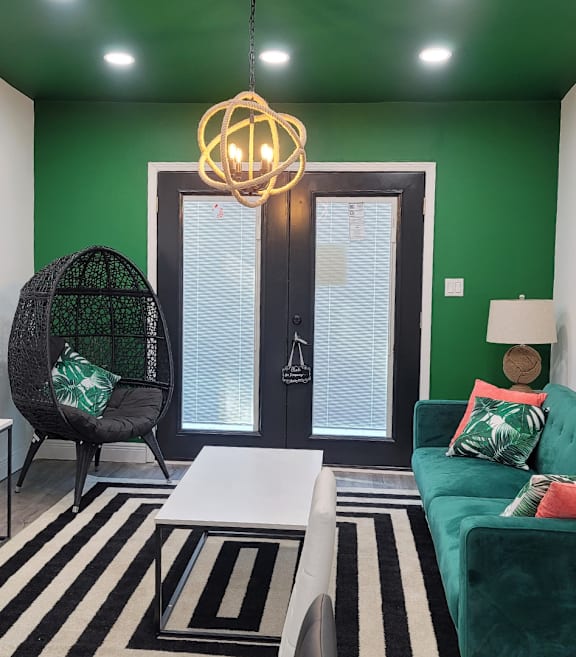 a living room with a green wall and a black and white striped rug