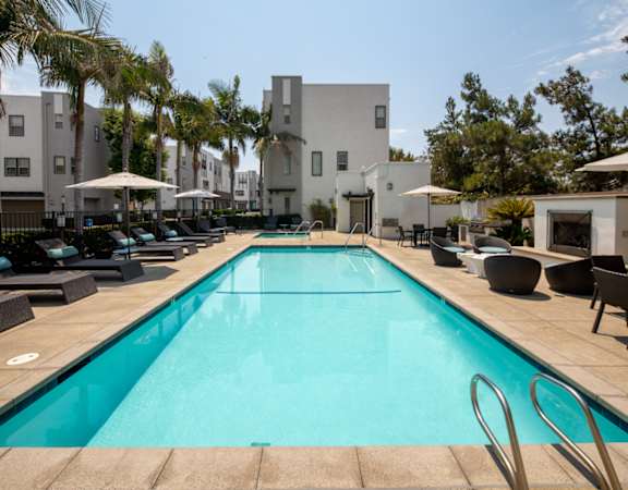 A swimming pool surrounded by lounge chairs and umbrellas.