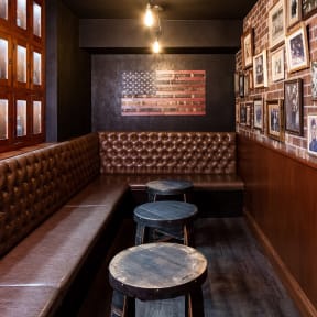 a bar with leather booths and tables and a flag on the wall