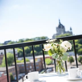 a vase with flowers on a table on a balcony