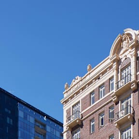 A tall, ornate building stands next to a modern glass building.