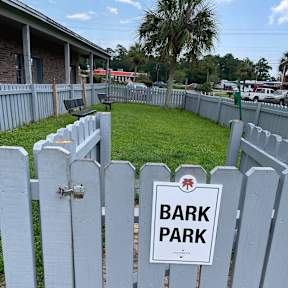a white fence with a bark park sign on it