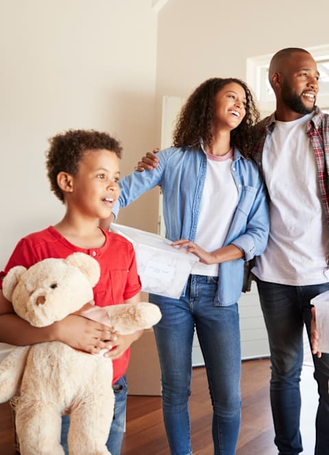 A family moving into a new home, carrying boxes labeled "bedroom" and "kitchen".