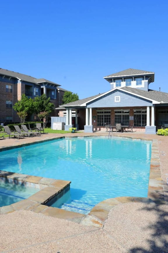a swimming pool with orange chairs and a building in the background