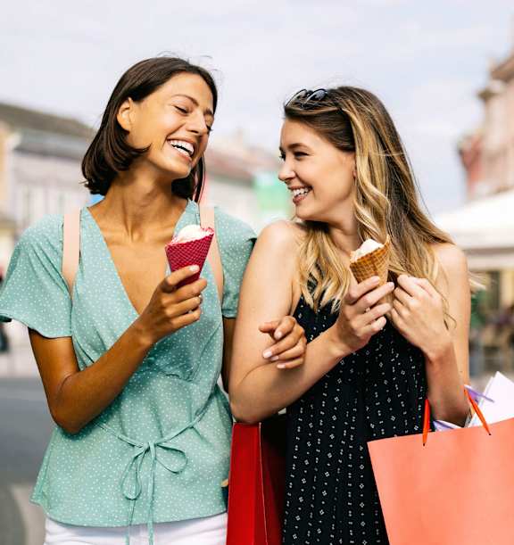 Two women laughing and holding ice cream cones and shopping bags.at Montage, Tigard, 97223