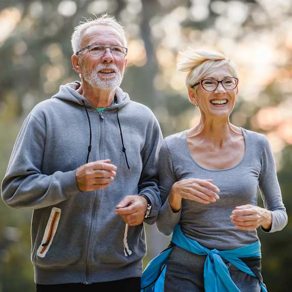 An older couple is jogging outdoors.