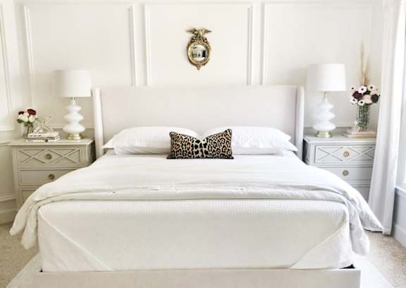 A white bedroom with a large bed and two nightstands.