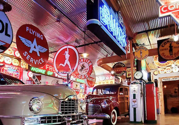 A vintage car is parked in a garage with a sign that says "Flying A Service" above it.