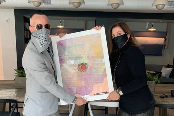 a man and a woman holding a picture and wearing face masks
