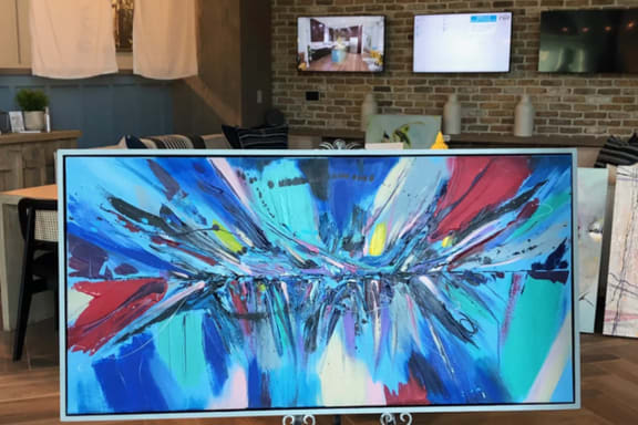 a painting on a monitor on a stand in a room
