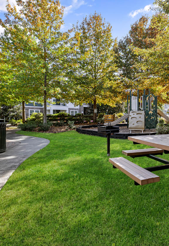 a picnic area with a picnic table and benches in front of a playground