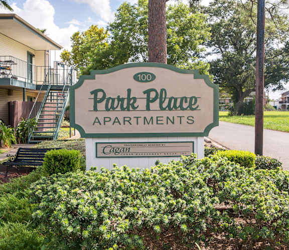 A sign for Park Place Apartments sits in front of a green shrub.