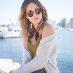 a woman wearing a scarf and sunglasses by the water