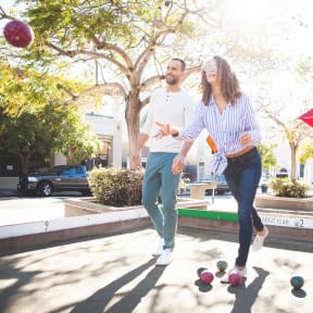 a man and a woman walking with balls on the ground