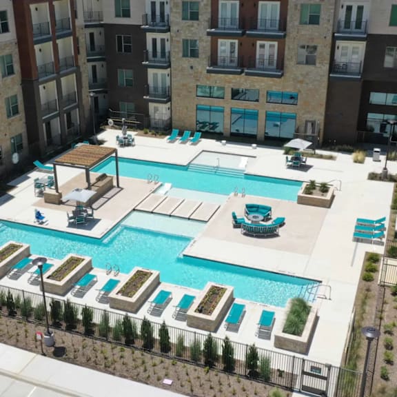 A large swimming pool surrounded by lounge chairs and umbrellas.