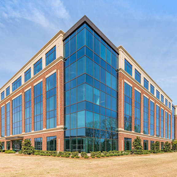 a large brick building with blue windows and a grassy area in front of it