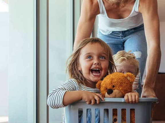 a little girl with a teddy bear in a laundry basket