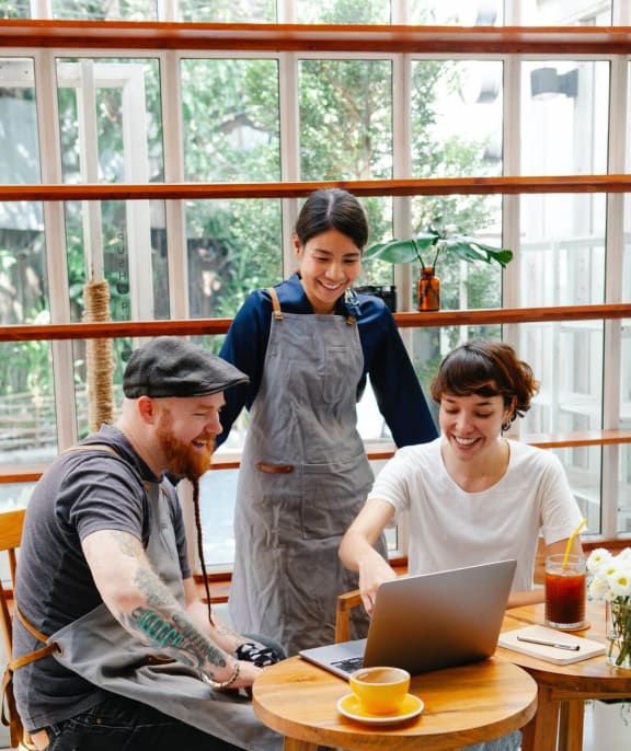 a group of people sitting around a table looking at a laptop