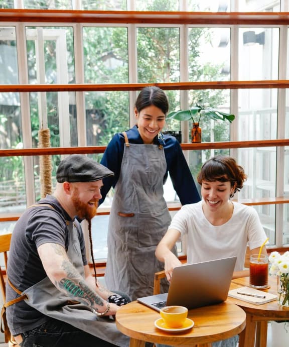 a group of people sitting around a table looking at a laptop