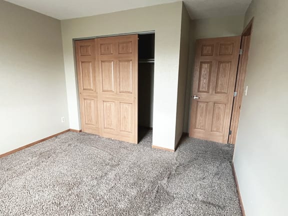 an empty room with a carpeted floor and two doors