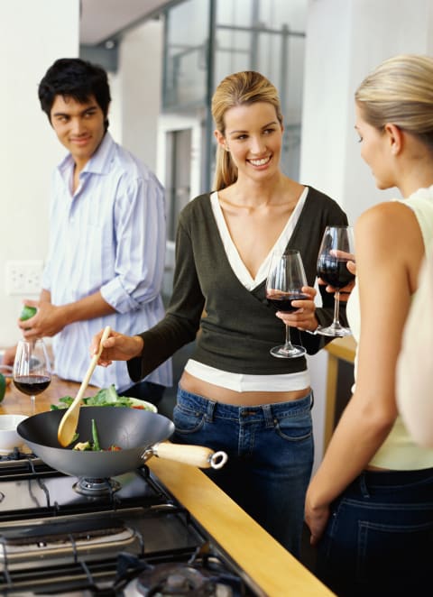 a group of people cooking and drinking wine in a kitchen at The Residences at Delmar DivINe, St Louis, MO