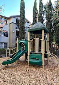A playground with a green slide and a green roof.