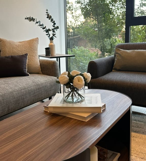 a living room with couches and a table with a vase of flowers