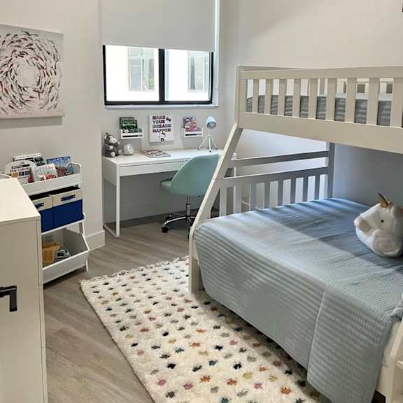 A child's bedroom with a bunk bed and a desk.