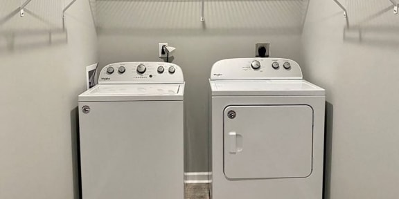 two washes and dryers in a laundry room with shelves