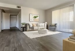 A living room with a grey floor and a white rug. at Parkway at Silverado Ranch, Las Vegas, NV
