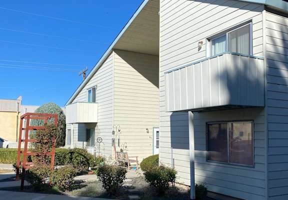 A house with a white siding and a red chair in front of it.