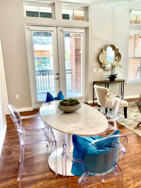 A dining room with hardwood-style flooring with access to a living room and near a double door entrance to a private balcony.