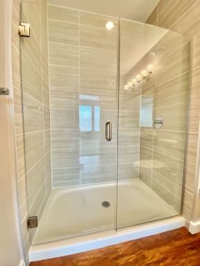 A large walk-in shower with glass doors and and modern floor-to-ceiling tile walls.
