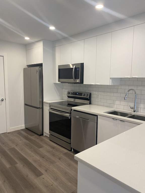a renovated kitchen with stainless steel appliances and white cabinets