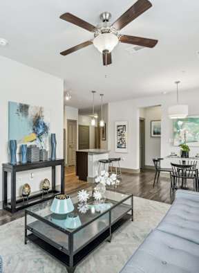 A modern living room with a glass coffee table and a grey sofa.