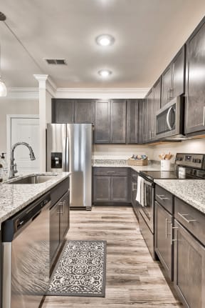 A modern kitchen with dark wood cabinets and stainless steel appliances.