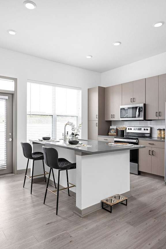 a kitchen with a large island with two black chairs at Slate at Fishers District, Fishers, Indiana