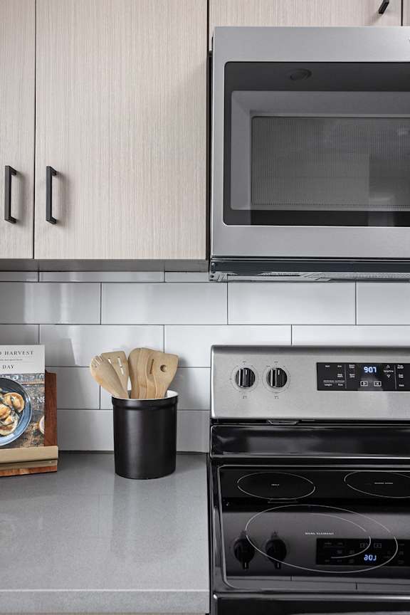 a kitchen with a stove and a microwave and a container of wooden spoons at Slate at Fishers District, Fishers, 46037