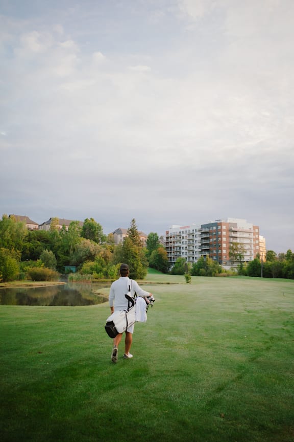 A man in a white shirt and shorts is walking across a grassy field.