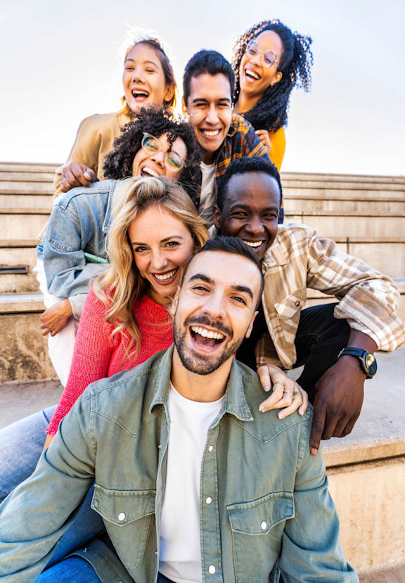 A group of people are sitting on a bench outdoors.