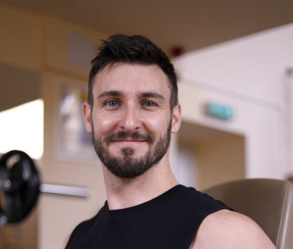 man smiling and lifting weights