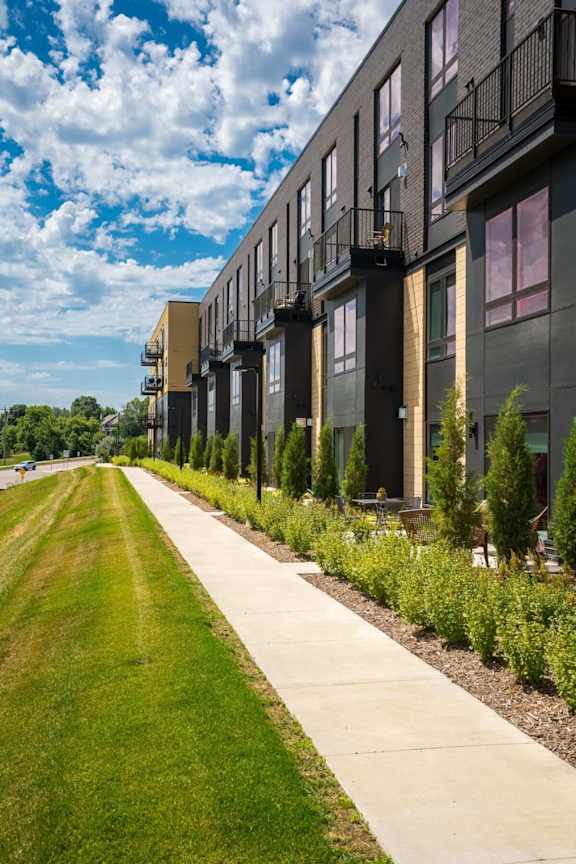 Exterior of Aspire at CityPlace with paved sidewalk, grass, and lush landscaping
