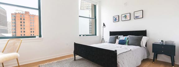 a bedroom with a bed and three windows at The Press/321, Detroit MI