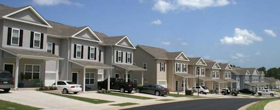 A row of houses with cars parked in front.