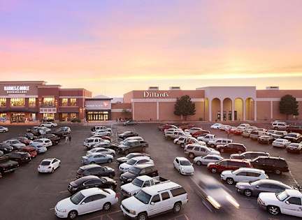A parking lot full of cars in front of a Dillard's store.