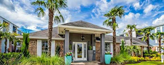 A house with a front yard featuring a brick pathway and a palm tree.