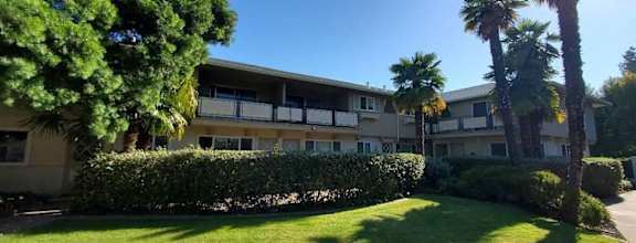 an apartment building with palm trees in front of it