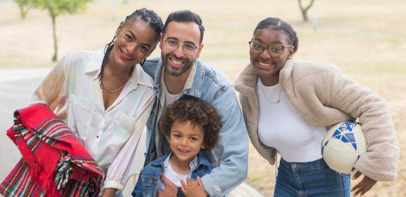 Happy diverse family smiling outside with outside activity accessories