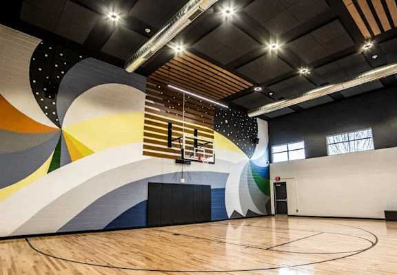 a basketball court in a gym with a colorful wall mural at The Century at Purdue Research Park-Student, West Lafayette, IN